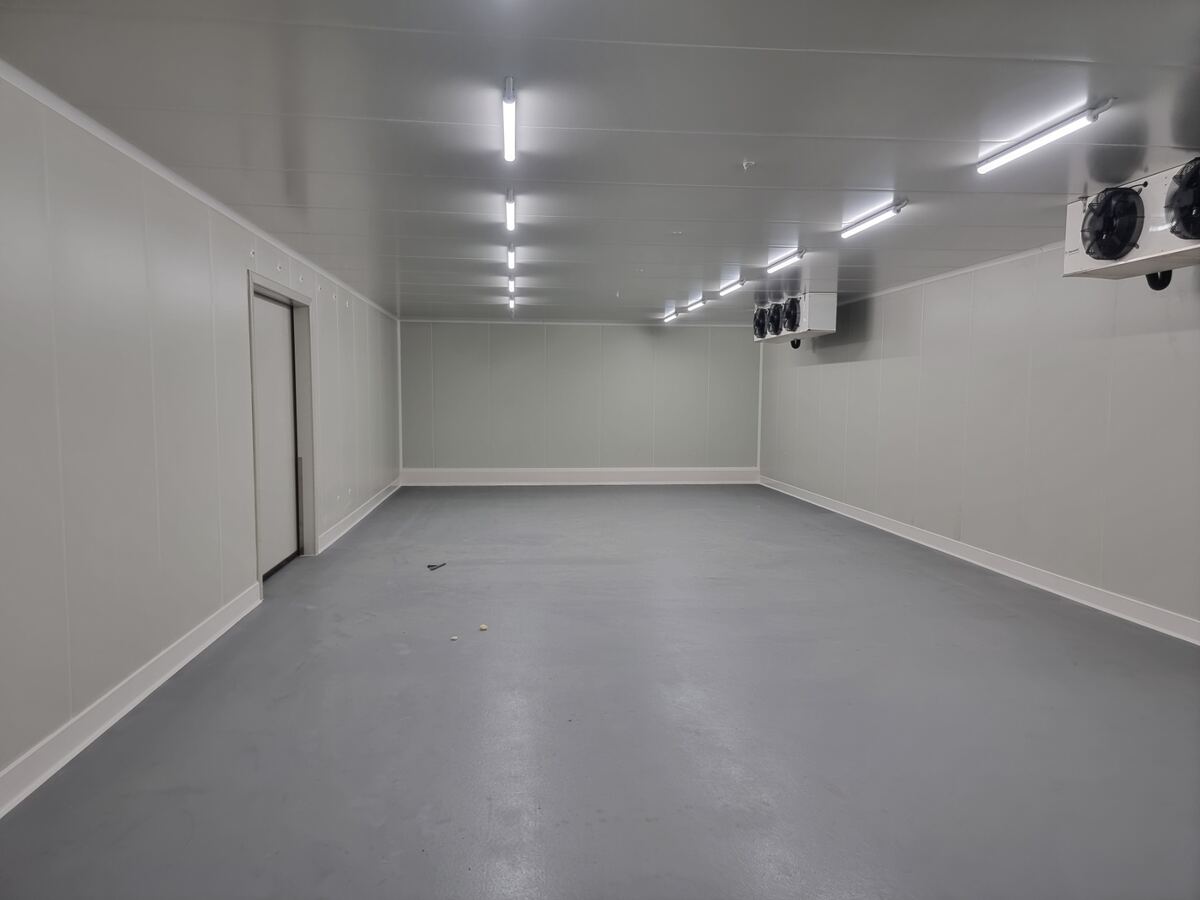 Empty freezer room with twin evaporator units mounted on ceiling